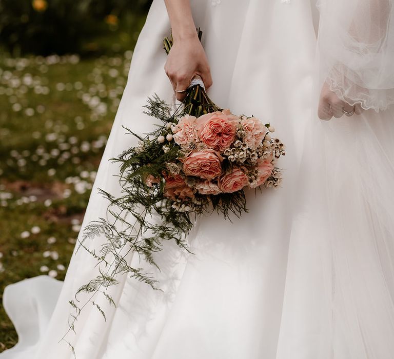 bride in a princess wedding dress with puff sleeves holding a pink David Austin rose and carnation wedding bouquet 