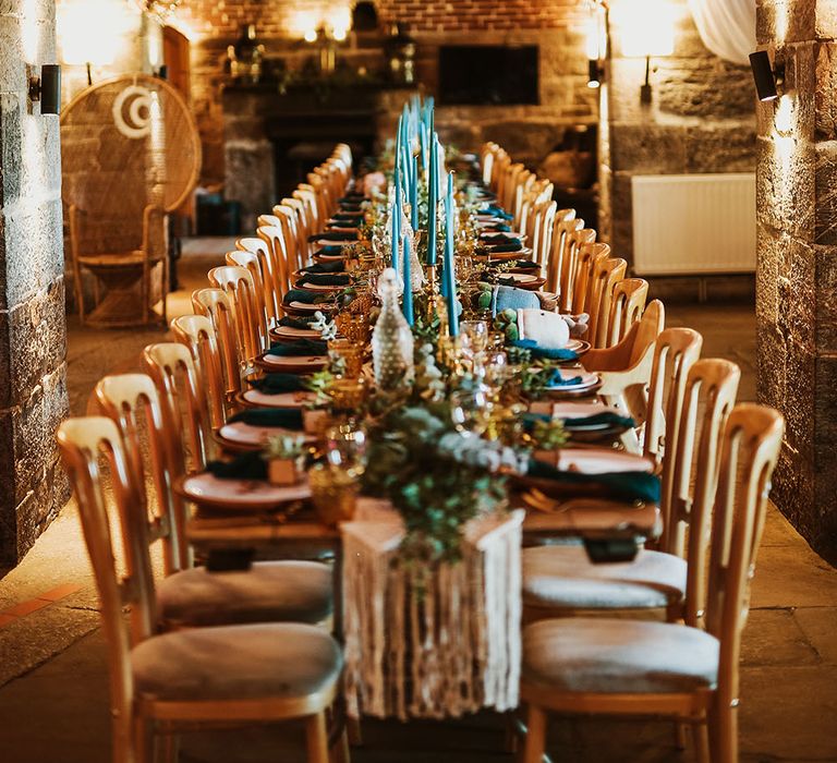 Boho wedding reception complete with blue candles and plant wedding favours with macrame table runner