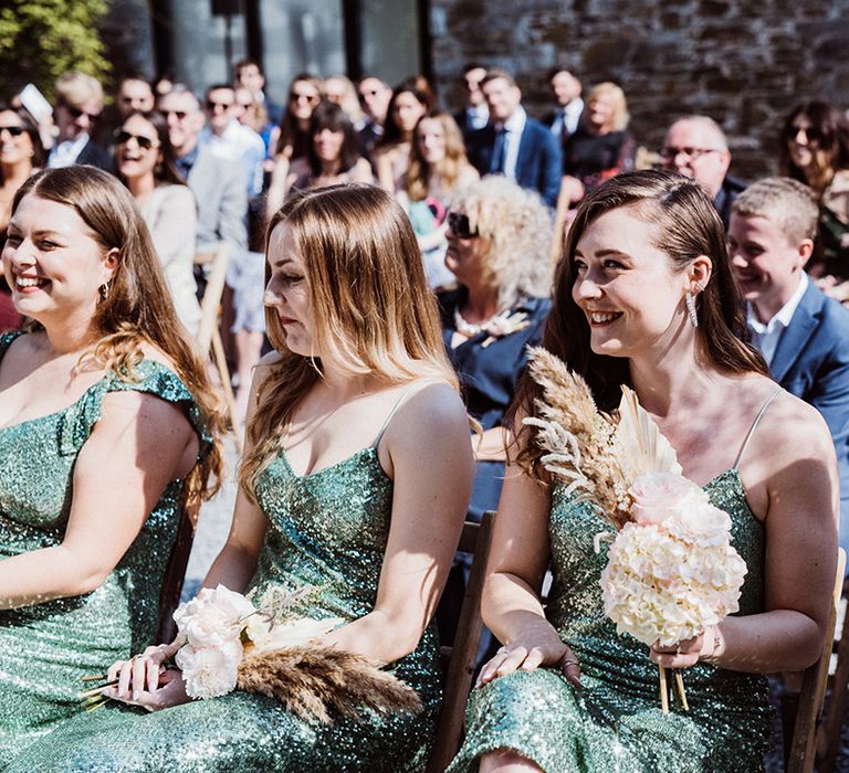 Bridesmaids holding dried flower bouquets in sequin green bridesmaid dresses 