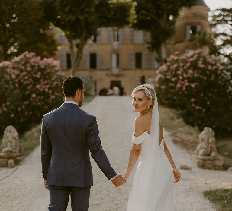 Bride wears her blonde hair in low-bun complete with pearl headband and floor-length veil