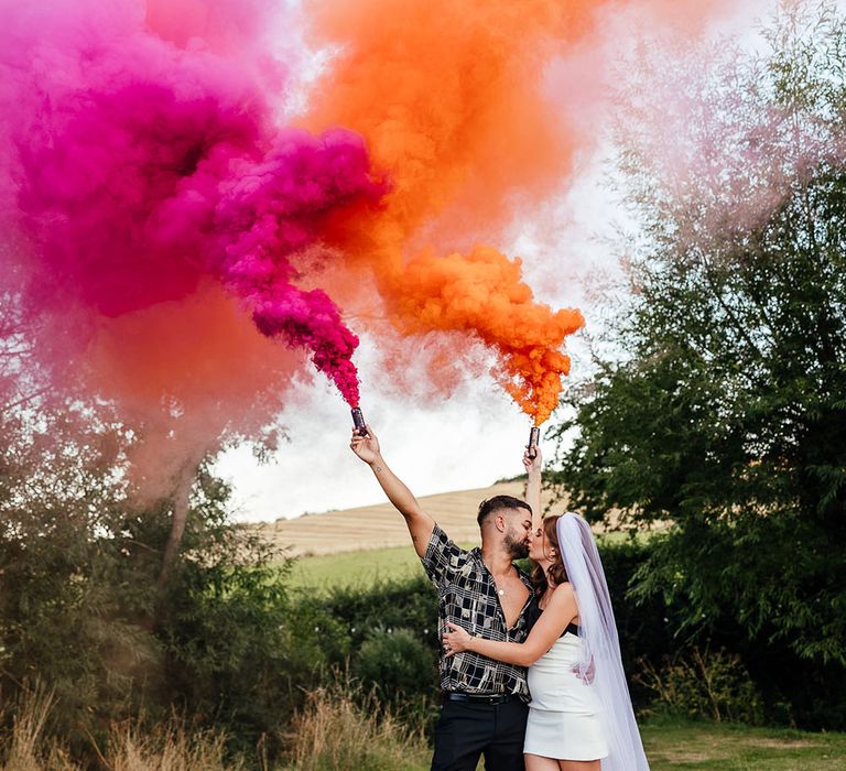 Bride & groom hold pink and orange smoke bombs for outdoor couples portraits