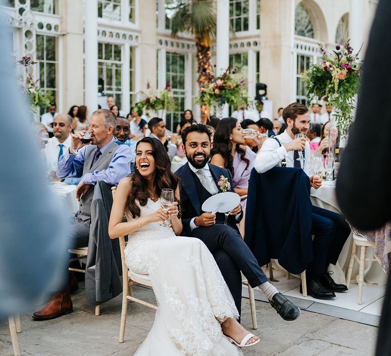 Bride & groom laugh during wedding speeches in the Great Conservatory at Syon Park