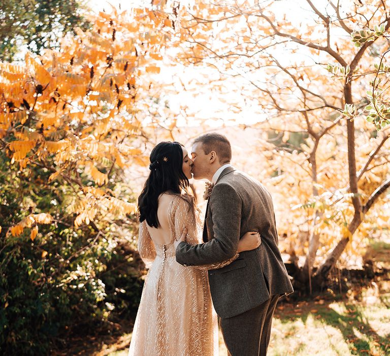 Bride in sparkly gold wedding dress kisses her groom outdoors after Lyde Court wedding