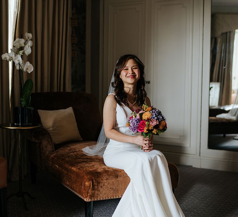 East Asian bride holds brightly coloured bouquet at The Dorchester before wedding day