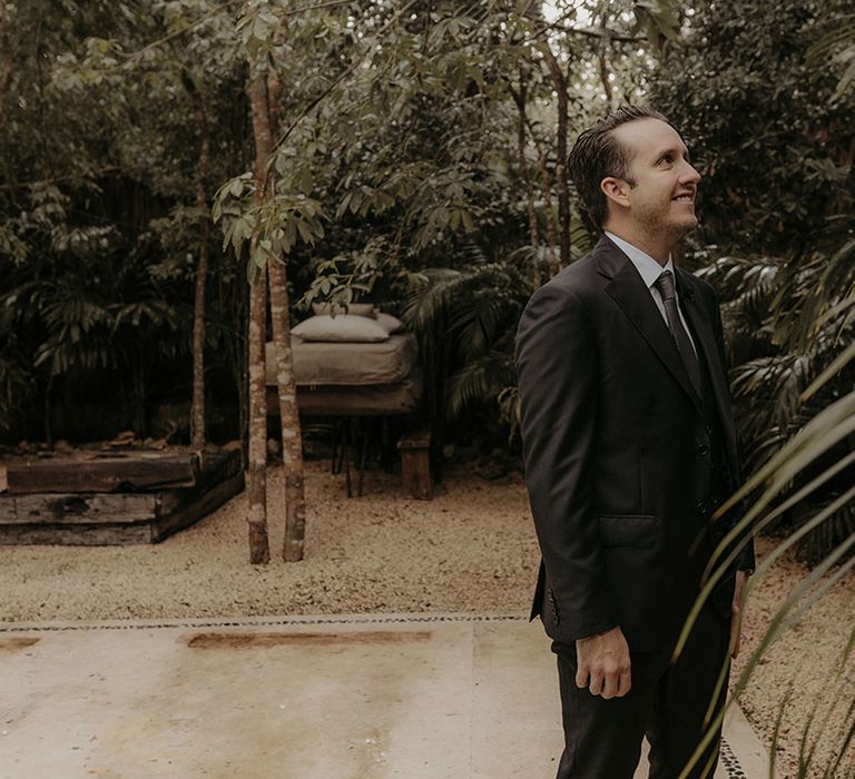 Groom awaits his bride outdoors during first look moment 