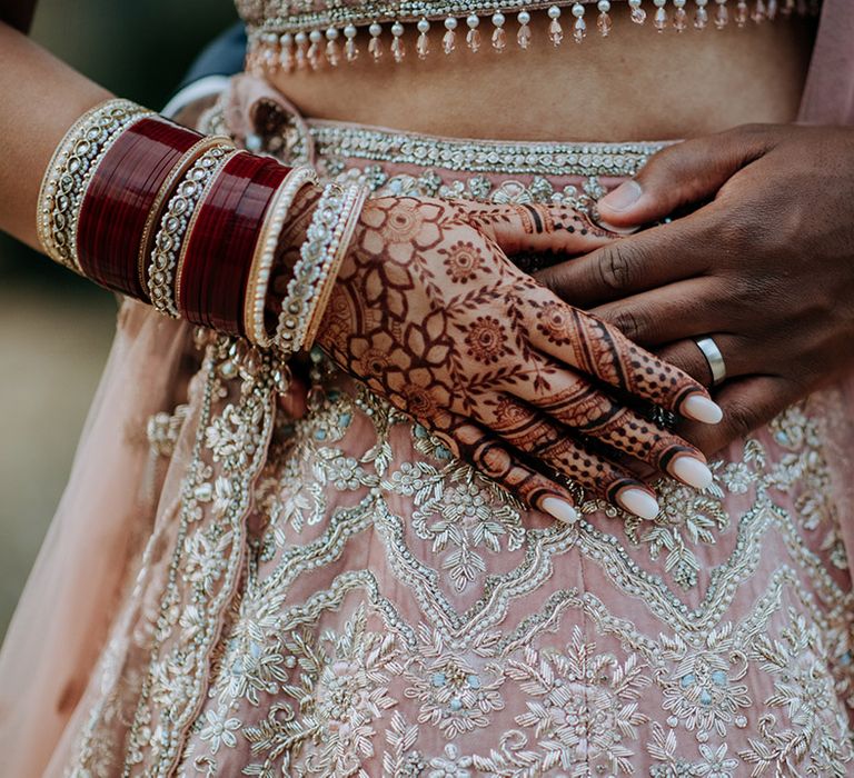 Close up of bridal Lehnga, bridal henna and the Groom's wedding ring