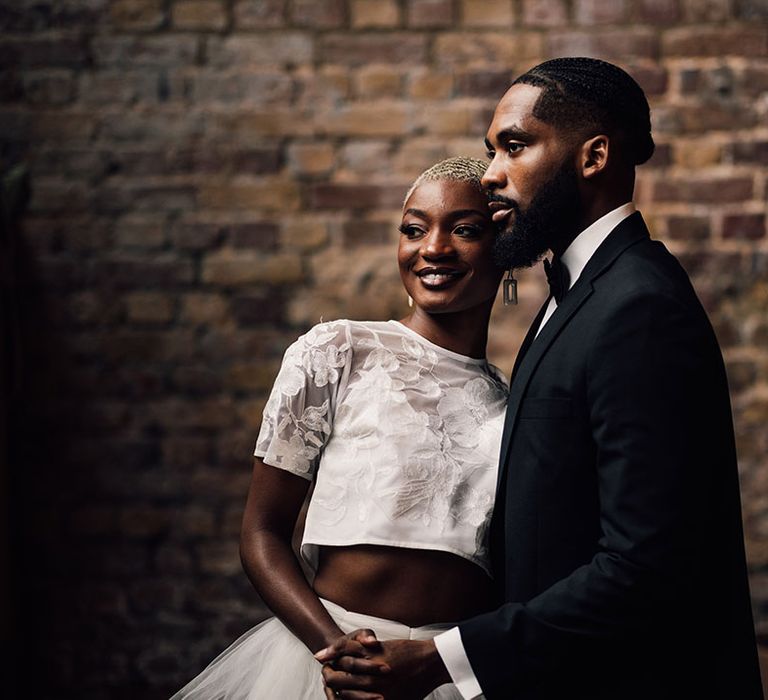 Black Bride and Groom portrait showing the Bride's embroidered floral wedding top and statement earrings for her wedding jewellery