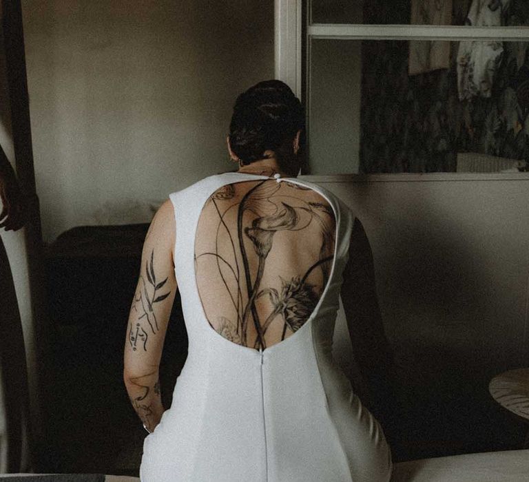 Lisa wears wears open-back fitted pre-loved wedding dress and showcases back tattoo