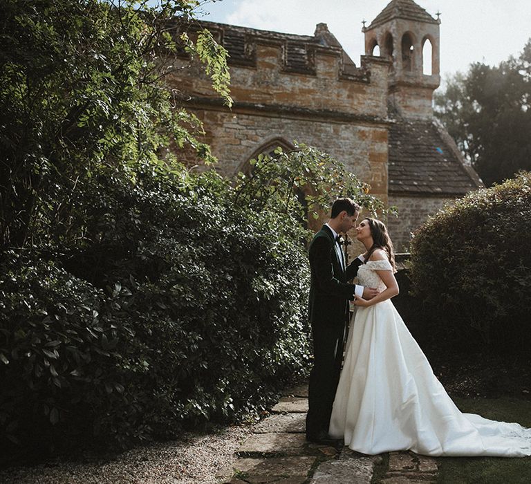 Traditional and classic country house wedding venue with the bride and groom standing together leaning in for a kiss 