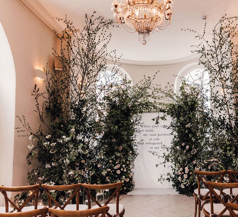 The altar decorations with large greenery column flower arrangements and a black and white minimal wedding sign