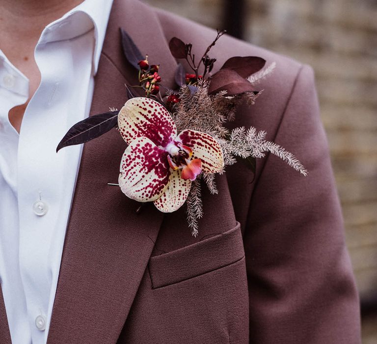 Groom in taupe coloured suit jacket with exotic flower buttonhole with orchid and foliage 