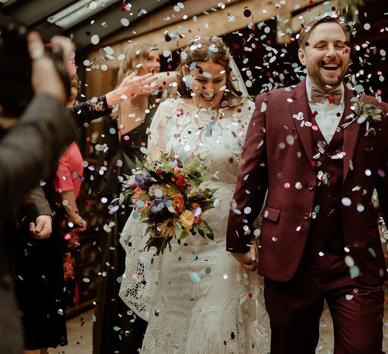 Newton Hall wedding in Northumberland with the bride and groom exiting from their wedding ceremony to confetti 