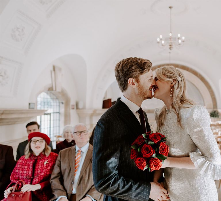 The bride and groom lean in to share three first kiss together as a married couple at their Halloween wedding 