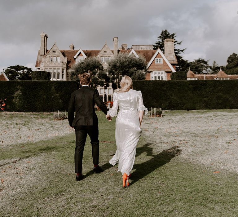 Bride in metallic wedding dress with bright orange wedding shoes with the groom in pinstriped suit for gothic wedding