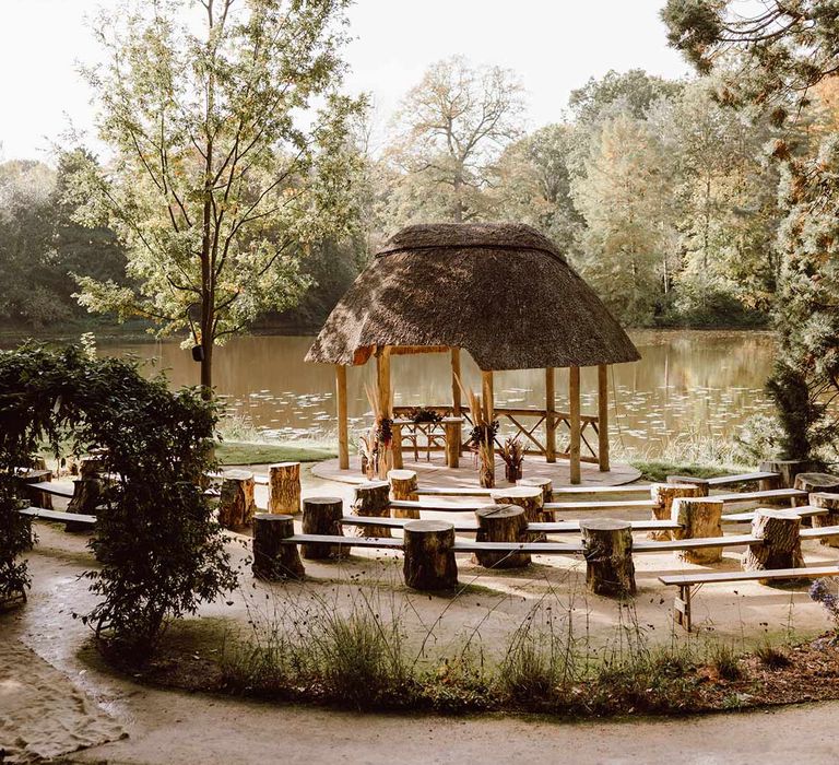 The Orangery Maidstone outdoor wedding venue with a Gazebo overlooking the lake and wooden benches with large decorate tree stump ends