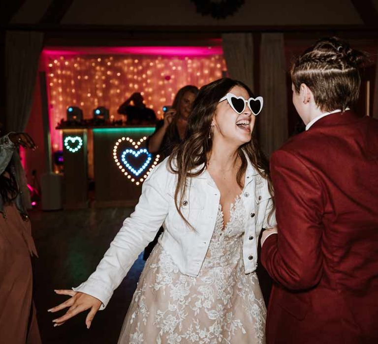 Bride in heart shaped wedding sunglasses dancing at wedding party with bride 