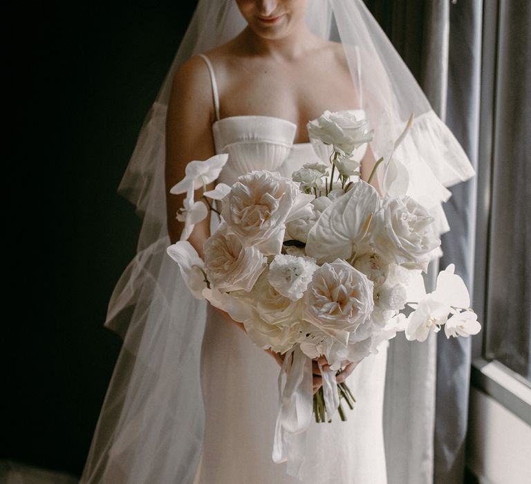 Bride holding her white wedding bouquet for the classic minimal style city wedding at Devonshire Terrace in a sleek satin wedding dress