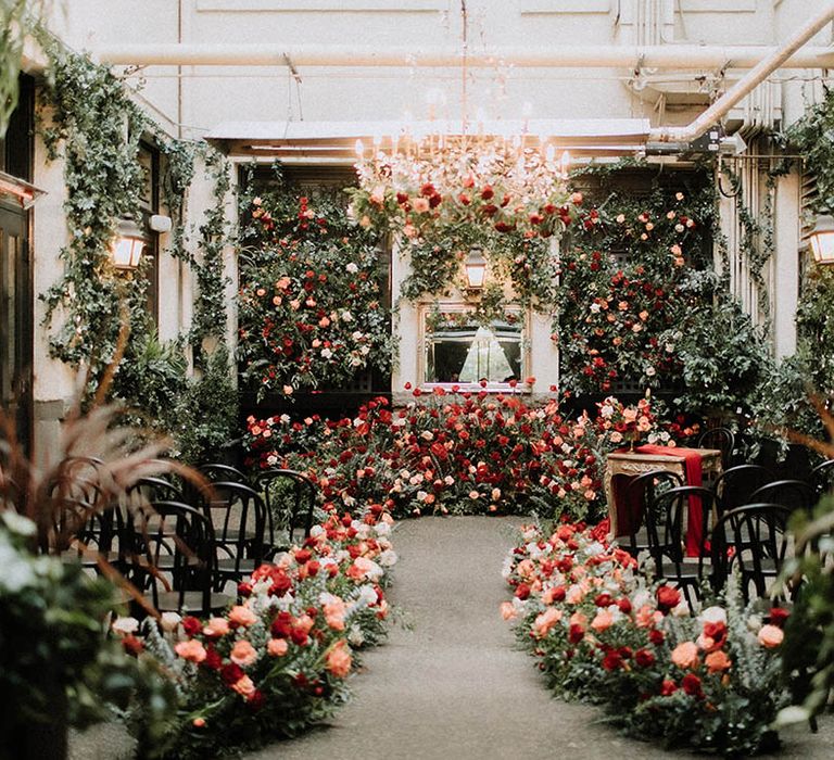 Stunning botanical wedding venue decorated with extravagant red wedding flowers and decor 