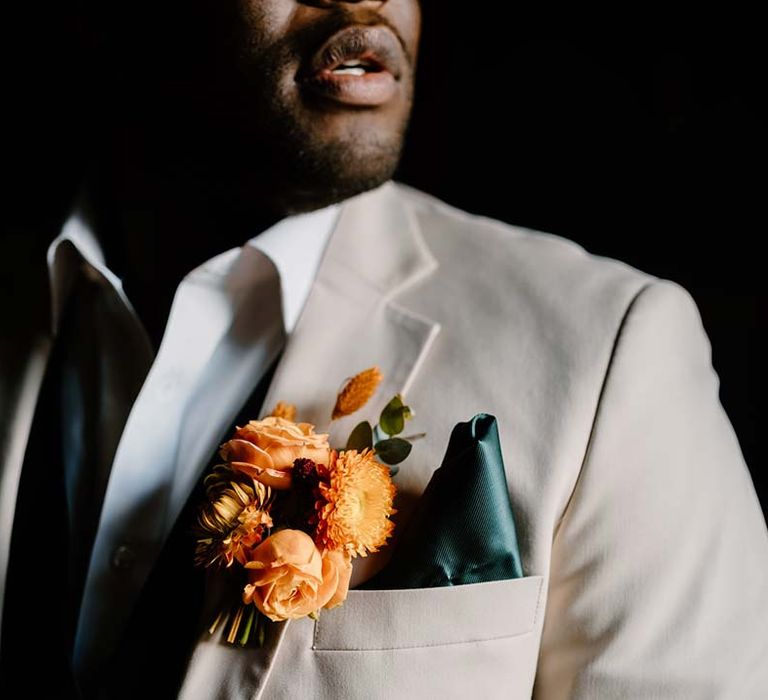 Groom in light grey grooms morning suit with white shirt, forest green pocket square and orange boutonniere 