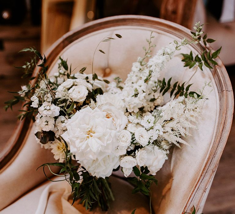 White bridal bouquet tied with white ribbon and green foliage 