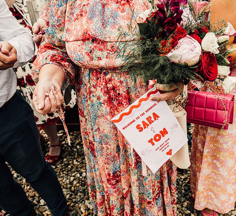 wedding guest holding the pink a red retro wedding programme on-the-day stationery 