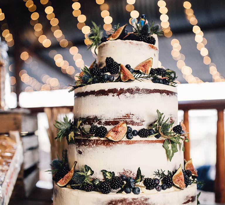 Semi naked rustic wedding cake with figs, berries, and foliage 