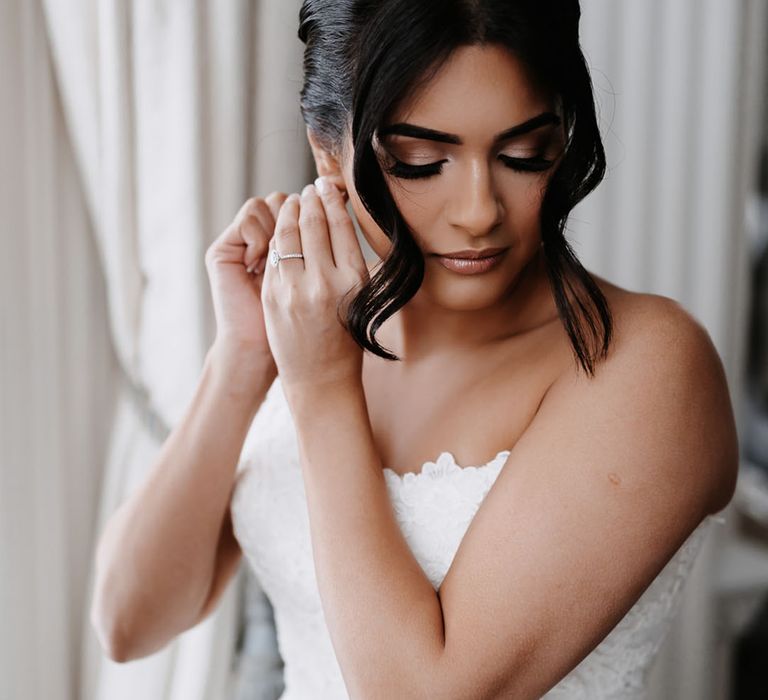 Bride wearing fitted lace wedding dress with beautiful dark hair in an updo with shimmering eye makeup 