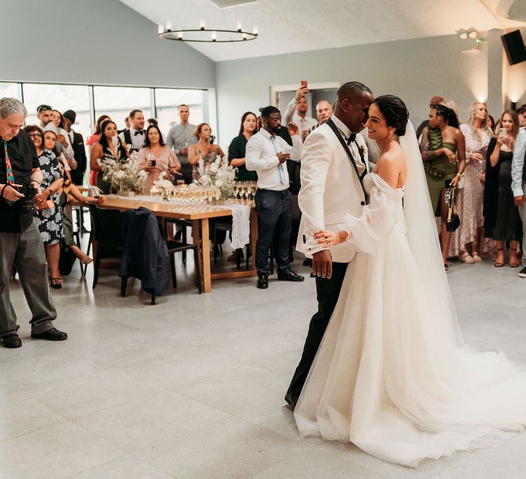 Bride in white tulle wedding dress shares first dance with groom in black and white tuxedo at Crumplebury wedding