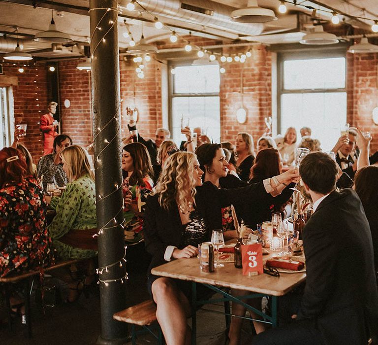 Boho wedding with the guests toasting to the newlyweds at the wedding breakfast 