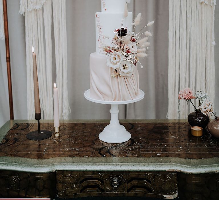 Three tier classic white wedding cake with bunny grass and dried flowers with macrame boho backdrop 