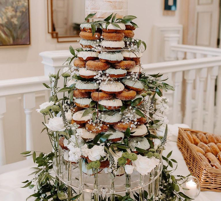 Sugar and white iced doughnut tower with white flowers and foliage with cake topper 