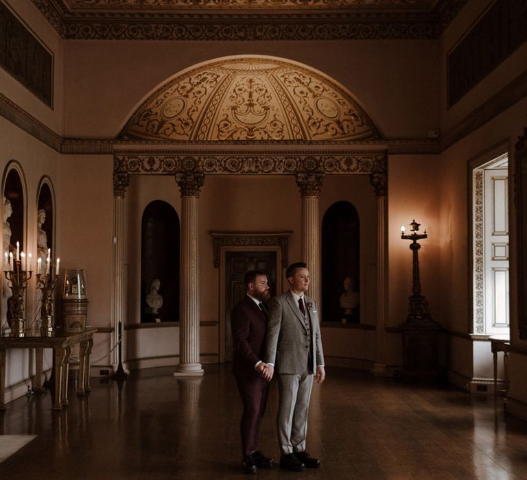 Two grooms holding hands at the iconic Syon Park wedding venue 