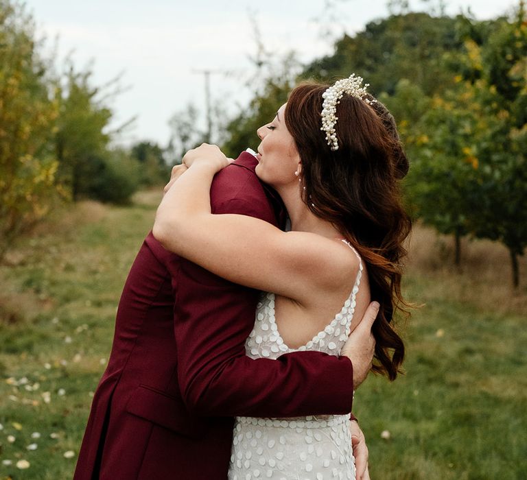 Bride in floral wedding dress with tiara embracing groom for sweet wedding photo 