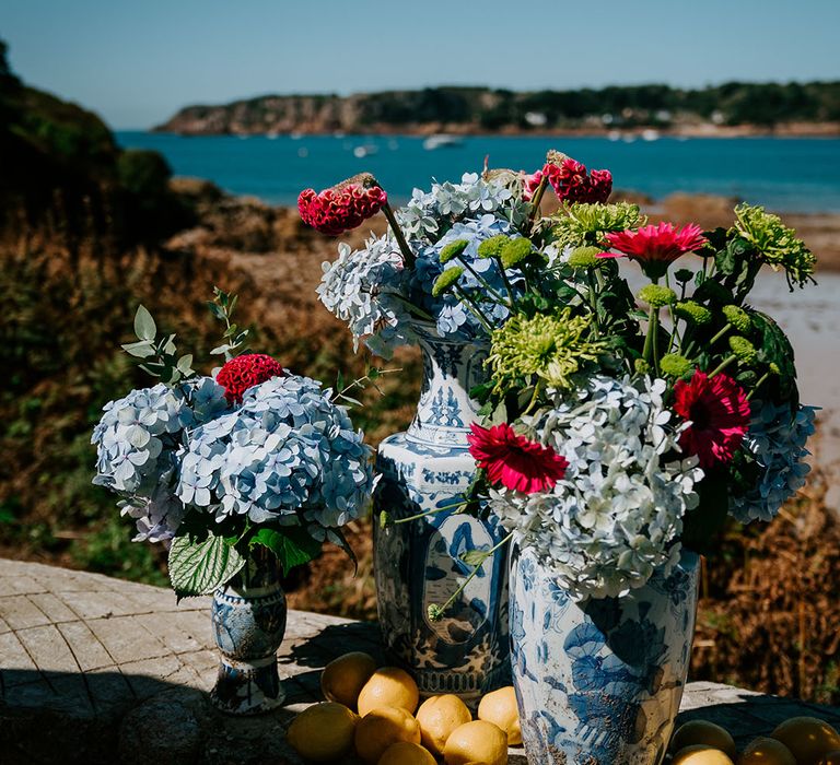 Blue and white floral patterned vase filled with blue hydrangeas and lemons 