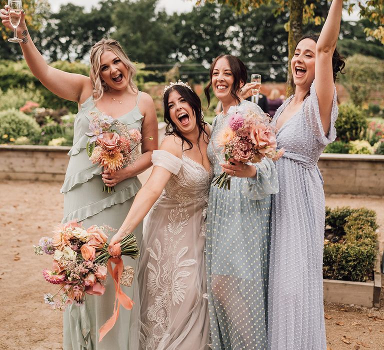 Bridesmaids wearing mismatched pastel bridesmaid dresses 