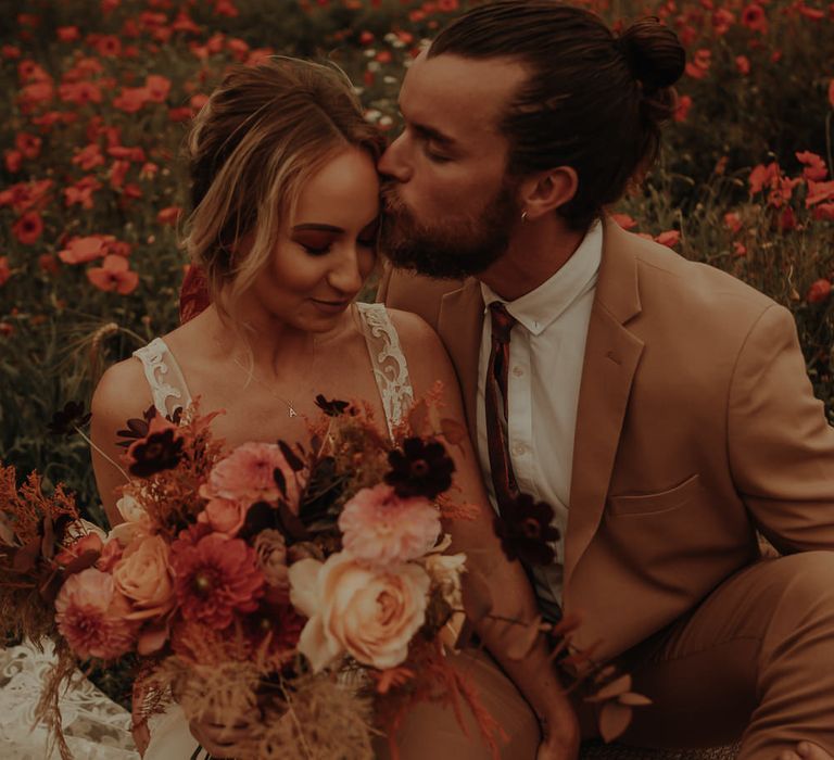 Groom kissing his bride on the head