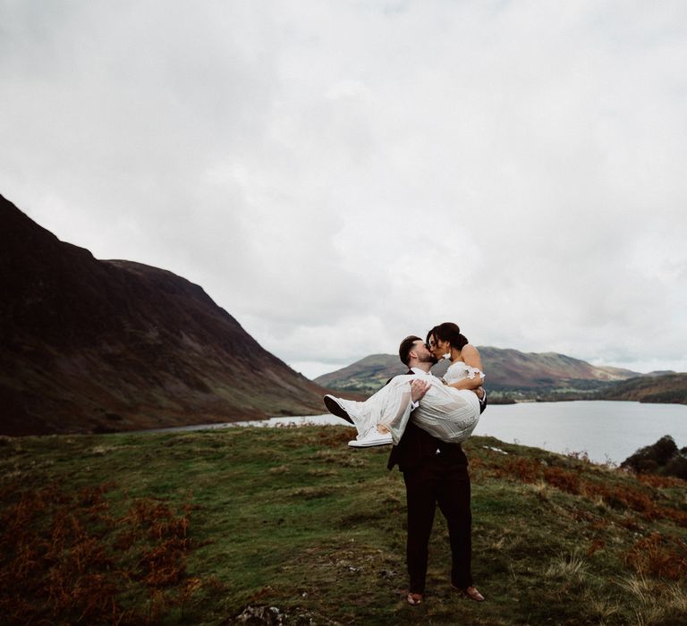 Groom carries bride in arms in Lake District 