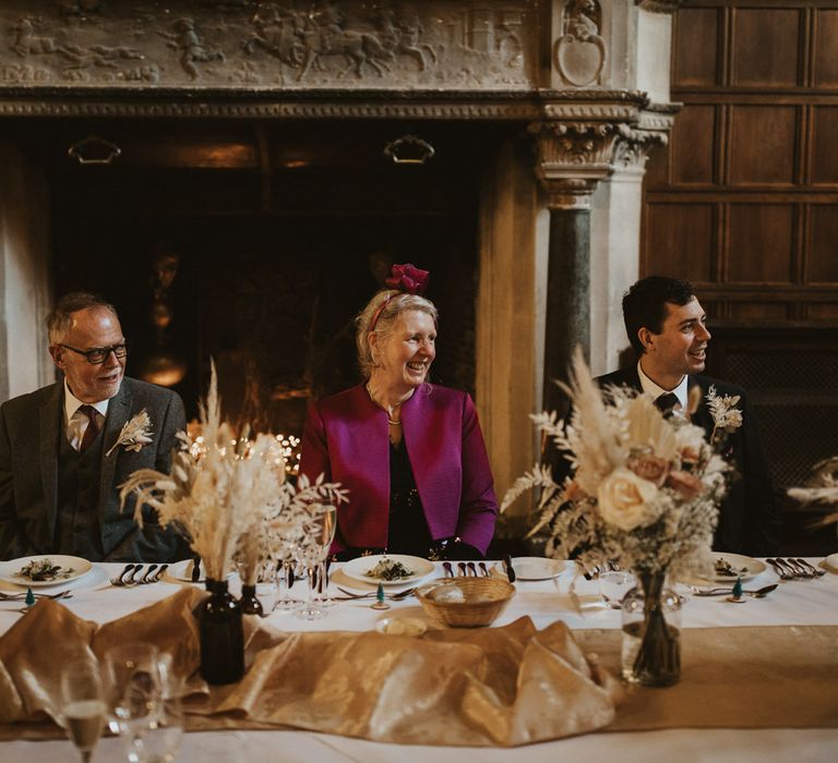 Top table with beige table runner and dried flowers in brown bottles 