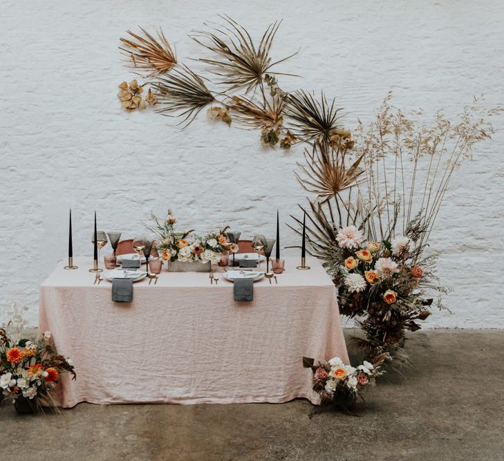 Minimal and sophisticated dried palm leaf arch over a linen wedding table setting