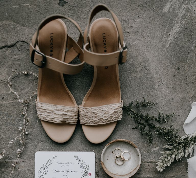 Minimalistic wedding stationery next to rings and wedding shoes