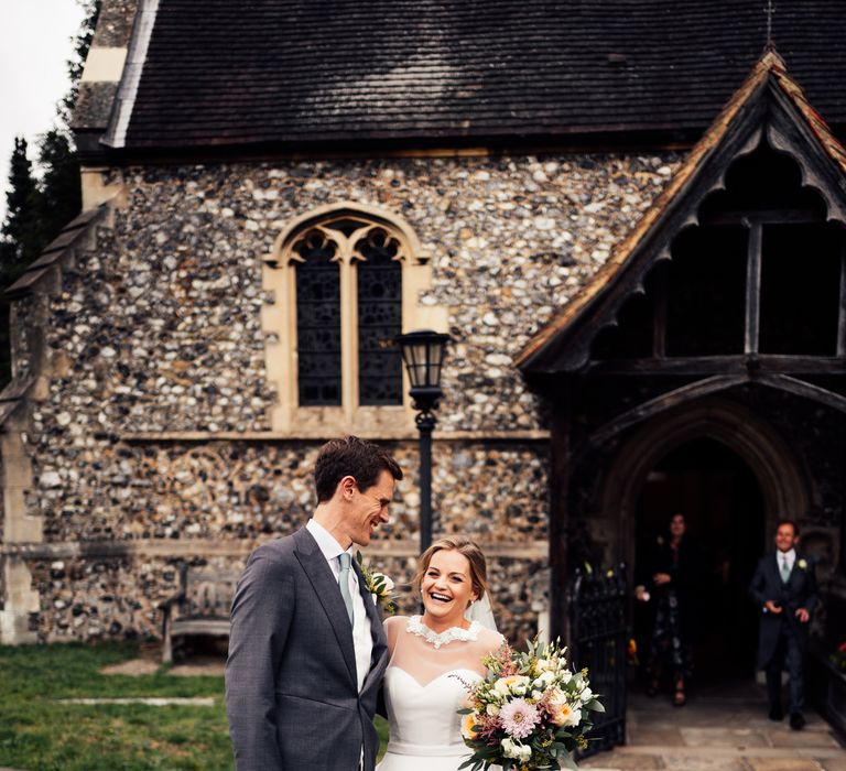 Bride & groom stand together outside of the church on wedding day