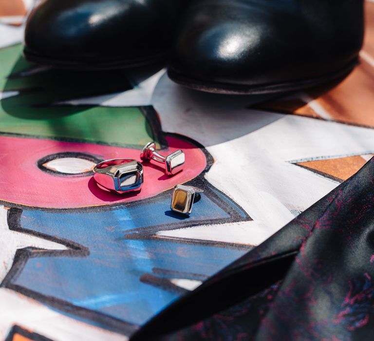 Silver ring and cufflink are upon colourful pop art