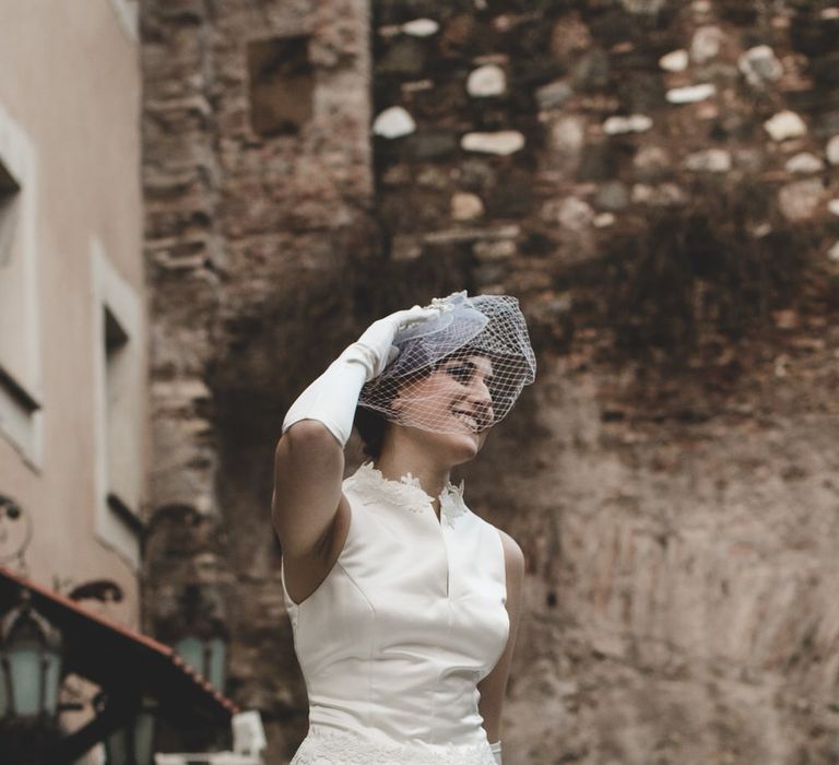 Bride wearing a vintage style mid length wedding dress with netted full underskirt, and vintage hat with net veil