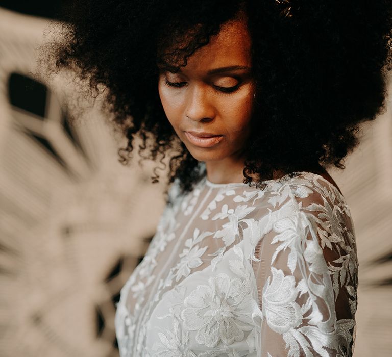 Bride looks down as she wears afro hair naturally with gold crown