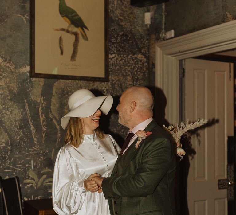 Bride & groom laugh together and hold hands on wedding day during reception