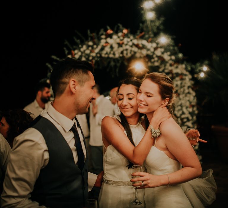 The bride and groom hugging a guest and smiling