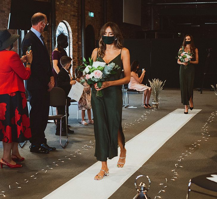 Bridesmaid in a forest green slip wedding dress walking down the aisle 