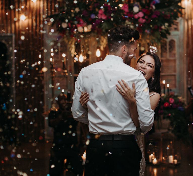 Bride and groom dancing in confetti at their moody romantic wedding reception