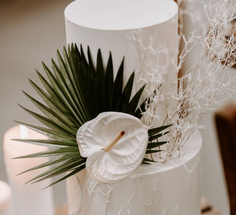 Two tier white wedding cake with palm leaf and white anthurium flower decoration