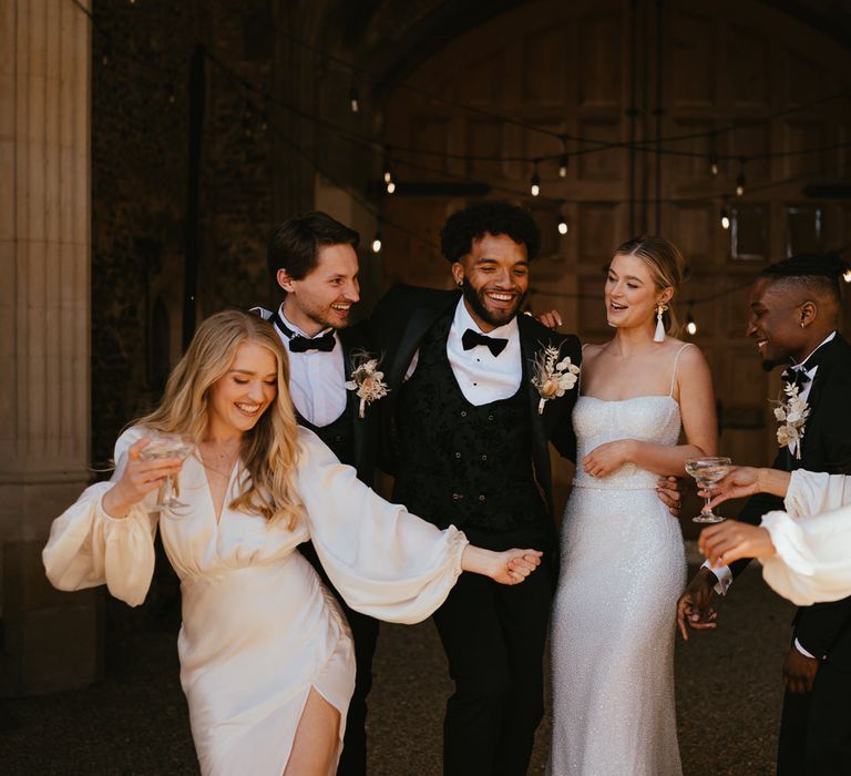 Wedding party portrait with bridesmaids in champagne satin dresses, and the groomsmen in black-tie suits 